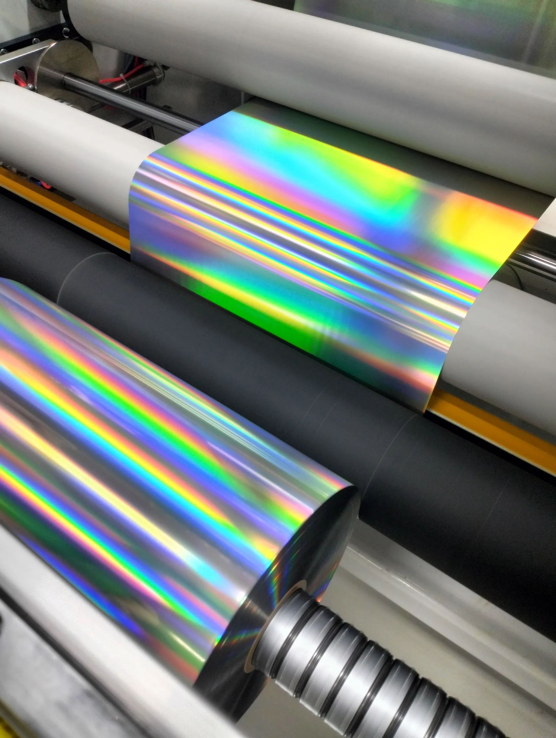 Holographic foil running through printing rollers